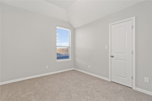 spare room with light carpet and vaulted ceiling