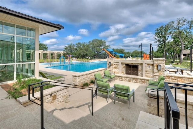 view of pool with an outdoor stone fireplace and a patio