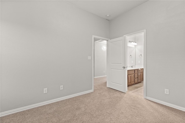 unfurnished bedroom with light colored carpet, sink, and ensuite bath