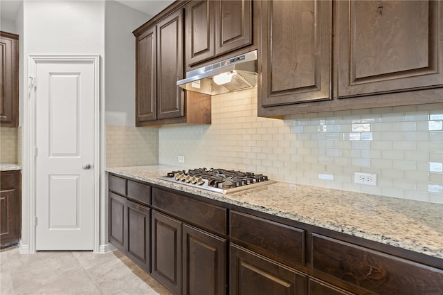 kitchen featuring decorative backsplash, light stone counters, dark brown cabinetry, and stainless steel gas cooktop