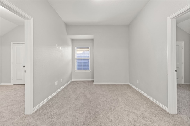 carpeted spare room with vaulted ceiling