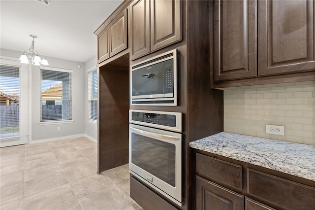 kitchen with light stone countertops, tasteful backsplash, dark brown cabinets, stainless steel appliances, and light tile patterned floors