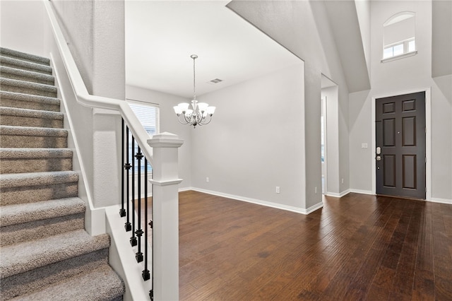 foyer with a towering ceiling, dark hardwood / wood-style floors, and an inviting chandelier