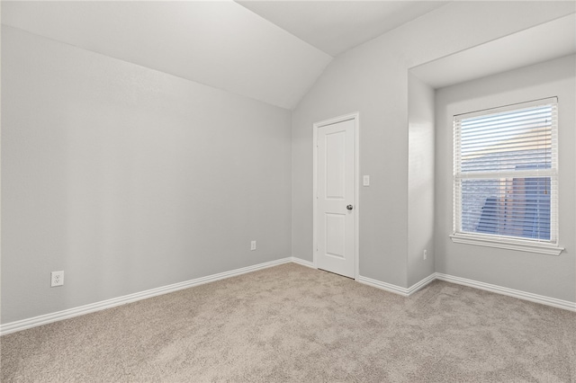 spare room with light carpet and lofted ceiling