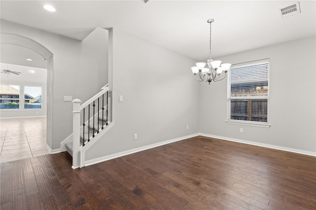 spare room featuring ceiling fan with notable chandelier and dark hardwood / wood-style floors