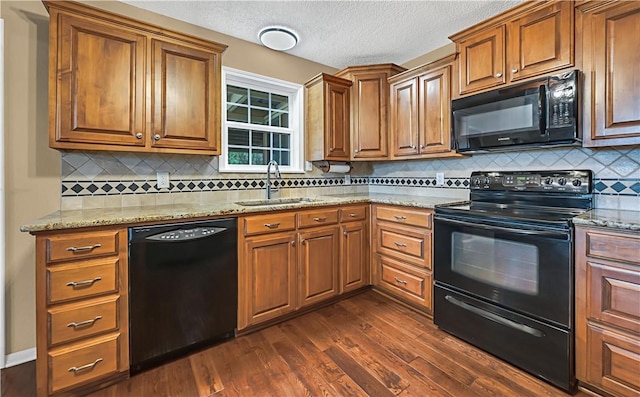 kitchen with decorative backsplash, light stone counters, sink, black appliances, and dark hardwood / wood-style floors