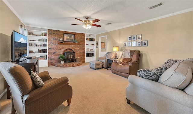 living room with built in shelves, light colored carpet, a wood stove, and crown molding