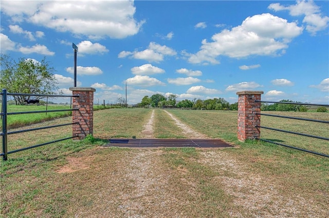 view of gate with a yard and a rural view