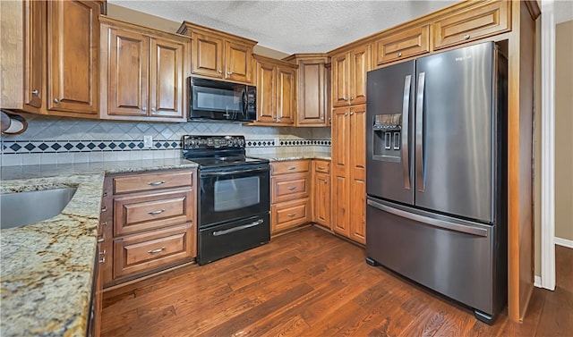 kitchen with tasteful backsplash, light stone counters, a textured ceiling, black appliances, and dark hardwood / wood-style floors