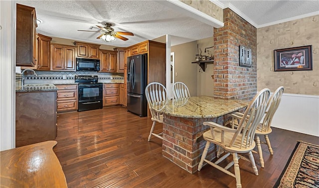 kitchen with light stone countertops, sink, dark hardwood / wood-style flooring, a breakfast bar, and black appliances