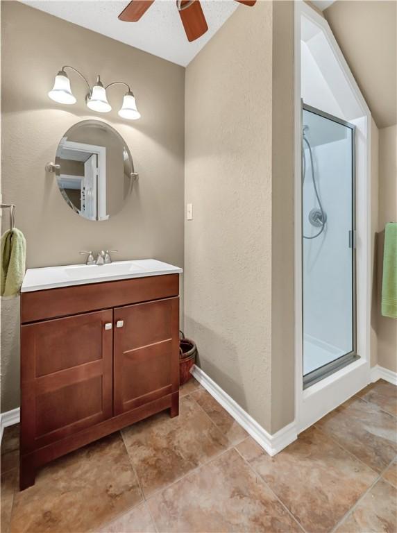 bathroom with vanity, ceiling fan, a shower with shower door, and lofted ceiling