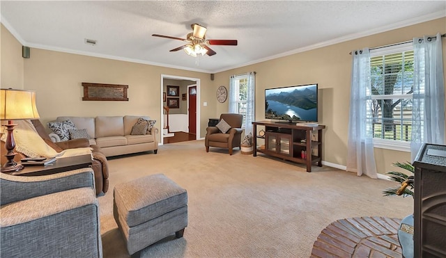 carpeted living room featuring crown molding, ceiling fan, and a healthy amount of sunlight