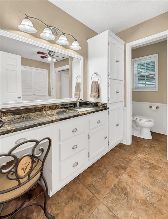 bathroom with vanity, toilet, and ceiling fan