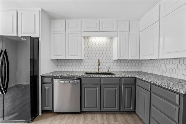 kitchen featuring white cabinets, dishwasher, black refrigerator, and sink