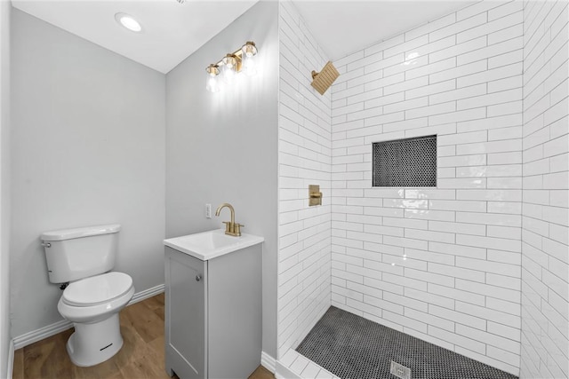 bathroom featuring vanity, toilet, wood-type flooring, and tiled shower