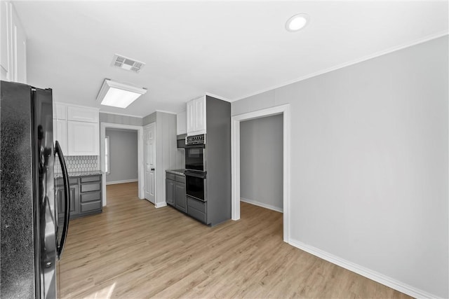 kitchen featuring backsplash, gray cabinetry, black appliances, light hardwood / wood-style flooring, and white cabinetry