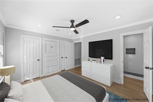 bedroom featuring two closets, ensuite bathroom, crown molding, ceiling fan, and light hardwood / wood-style floors