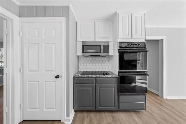 kitchen featuring gray cabinetry, stone counters, light hardwood / wood-style floors, white cabinets, and black appliances