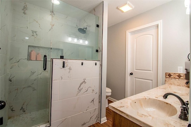 bathroom with hardwood / wood-style floors, vanity, toilet, and walk in shower