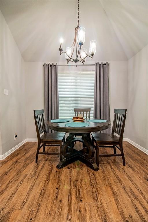 dining space featuring a chandelier, hardwood / wood-style floors, and vaulted ceiling