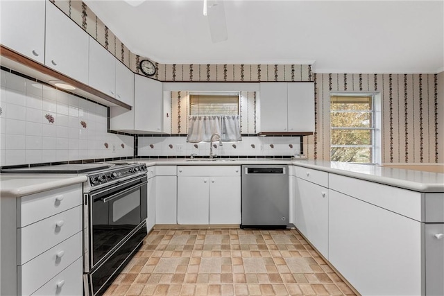 kitchen with black range oven, stainless steel dishwasher, white cabinetry, and a wealth of natural light