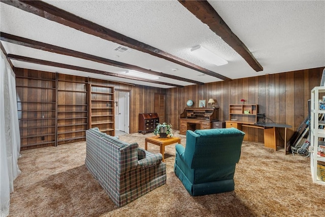 carpeted living room featuring beamed ceiling, wood walls, and a textured ceiling