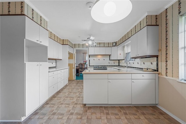 kitchen with white cabinets, ceiling fan, ornamental molding, and kitchen peninsula