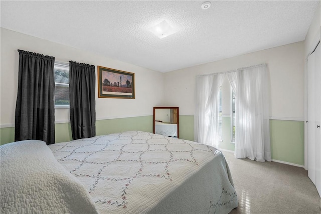 bedroom with multiple windows, light carpet, and a textured ceiling