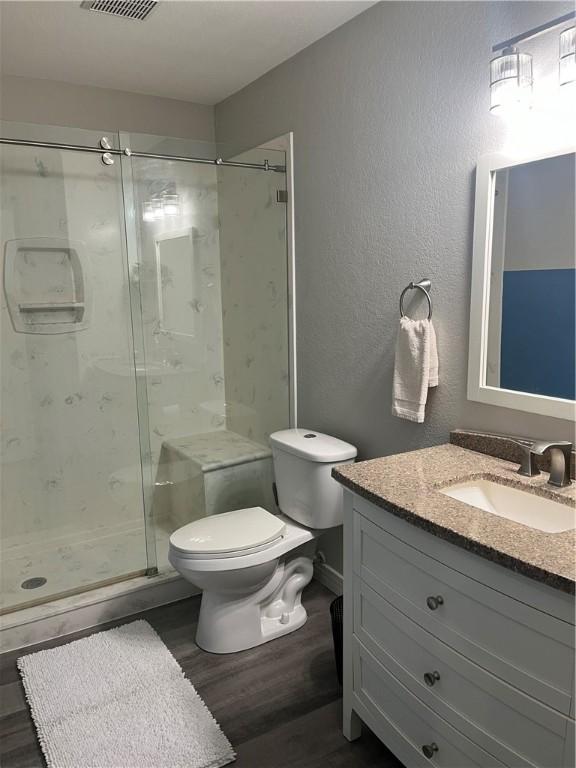 bathroom featuring vanity, hardwood / wood-style flooring, toilet, and walk in shower