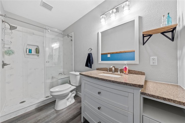 bathroom with hardwood / wood-style floors, vanity, toilet, and a shower with door