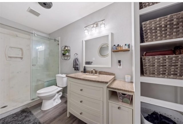 bathroom with hardwood / wood-style floors, vanity, toilet, and a shower with door