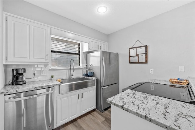 kitchen with white cabinets, sink, decorative backsplash, light wood-type flooring, and appliances with stainless steel finishes