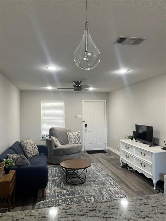 living room with ceiling fan and dark wood-type flooring