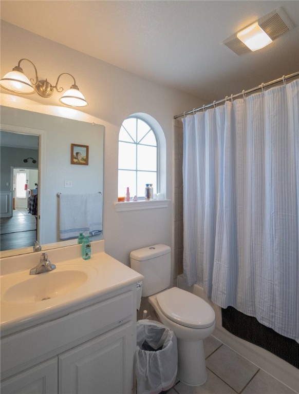 full bathroom featuring toilet, tile patterned flooring, shower / bath combination with curtain, and vanity