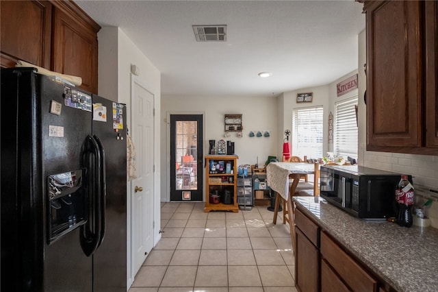 kitchen featuring backsplash, light tile patterned floors, and black appliances