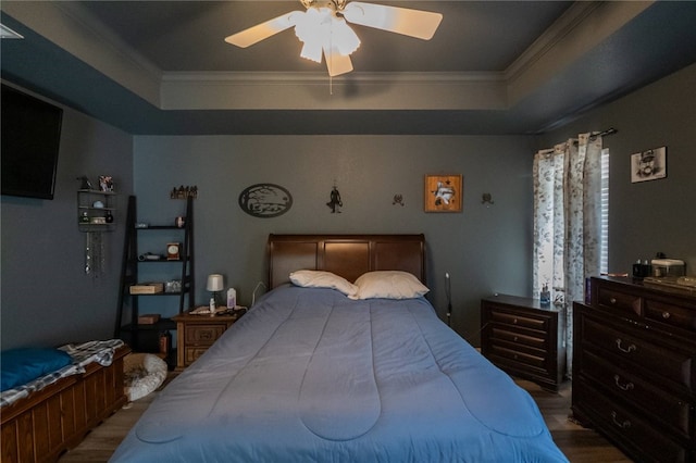 bedroom featuring a raised ceiling, ceiling fan, hardwood / wood-style flooring, and crown molding