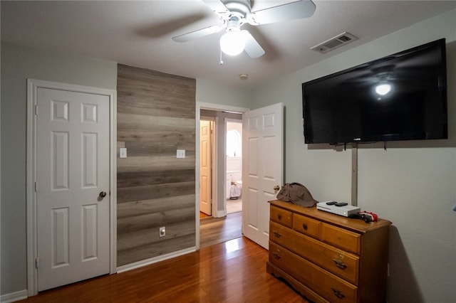 bedroom featuring ceiling fan, wooden walls, and wood-type flooring