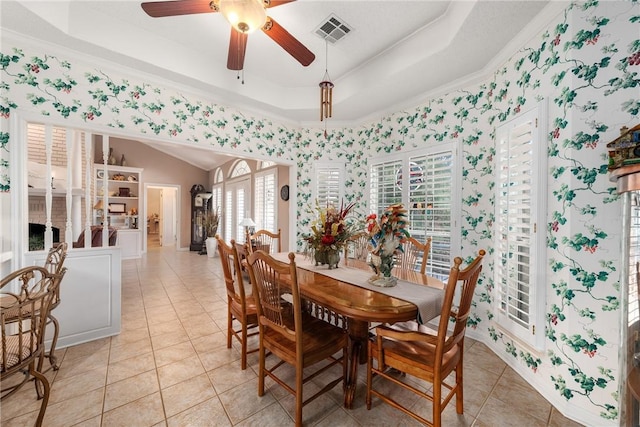 dining area with a raised ceiling, ceiling fan, crown molding, and light tile patterned flooring