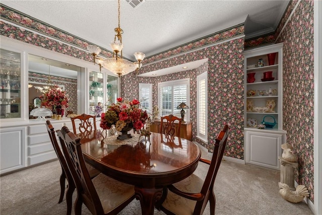 dining room with a chandelier, crown molding, light colored carpet, and a textured ceiling