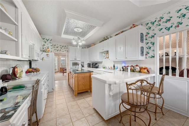 kitchen featuring white appliances, white cabinets, hanging light fixtures, light tile patterned floors, and kitchen peninsula