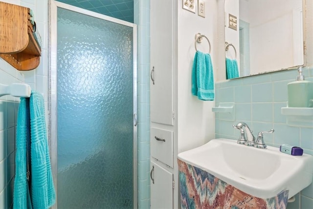 bathroom with tasteful backsplash, tile walls, walk in shower, and sink