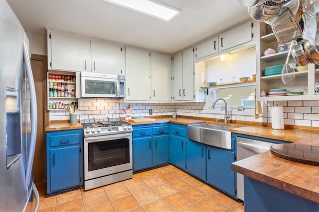 kitchen with backsplash, stainless steel appliances, blue cabinets, sink, and butcher block counters