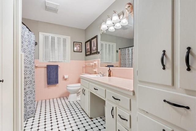 bathroom with tile patterned flooring, vanity, toilet, and tile walls