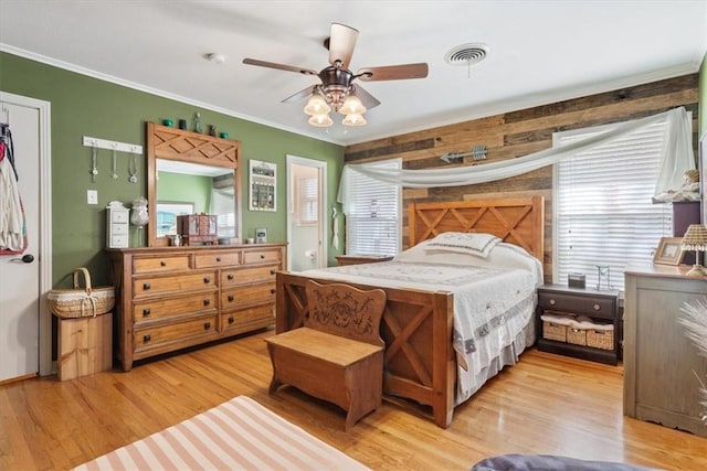 bedroom featuring ceiling fan, light hardwood / wood-style floors, ornamental molding, and multiple windows