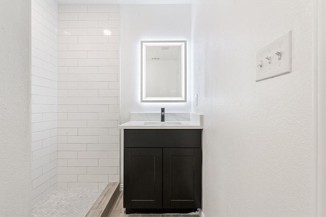 bathroom with vanity and a tile shower