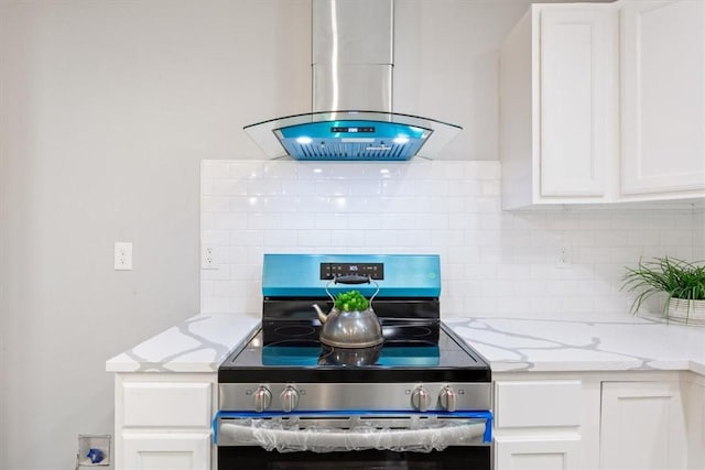 interior details with electric stove, island exhaust hood, and white cabinets