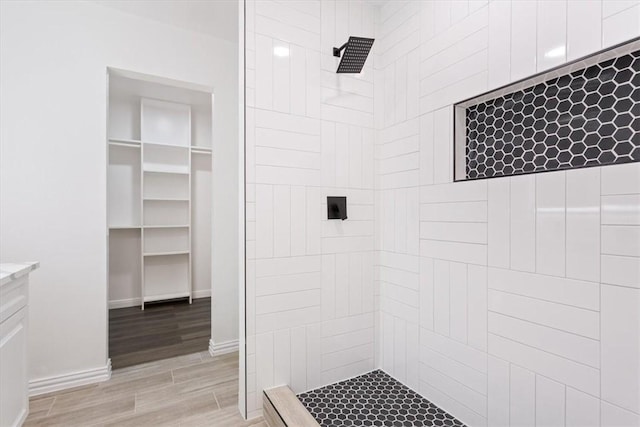 bathroom with hardwood / wood-style flooring, vanity, and tiled shower