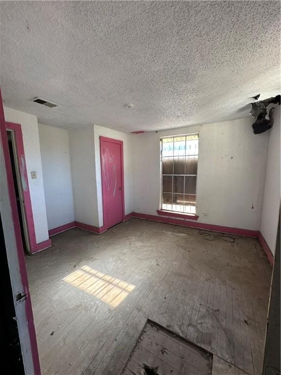 unfurnished room with hardwood / wood-style floors and a textured ceiling