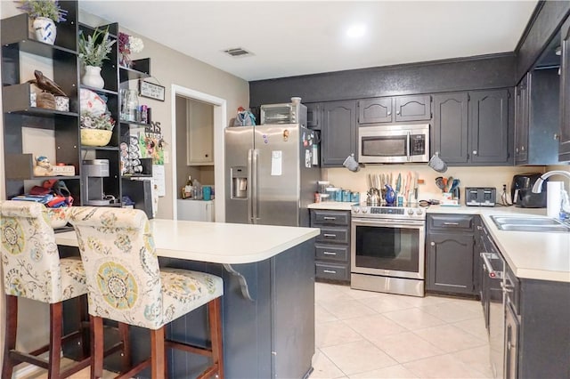 kitchen with a breakfast bar, appliances with stainless steel finishes, light tile patterned flooring, and sink