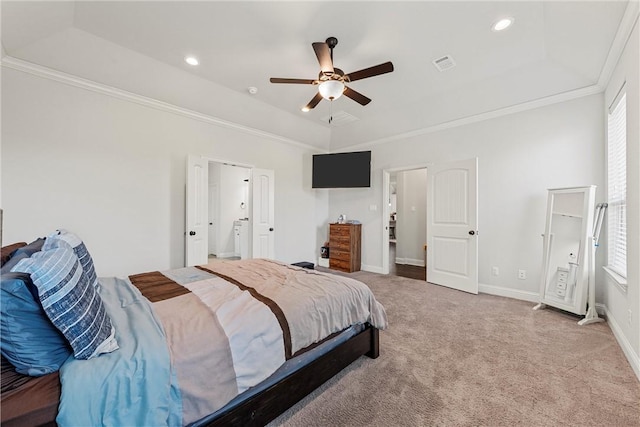 carpeted bedroom featuring a tray ceiling, crown molding, connected bathroom, and ceiling fan